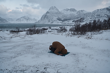 Image showing Muslim traveler praying in cold snowy winter day