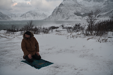 Image showing Muslim traveler praying in cold snowy winter day