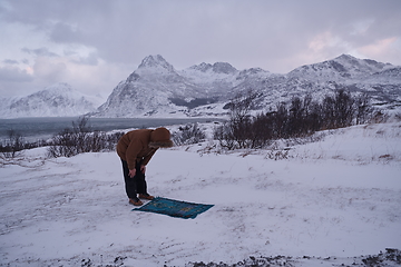 Image showing Muslim traveler praying in cold snowy winter day