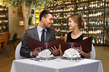 Image showing happy couple with menus at restaurant or wine bar
