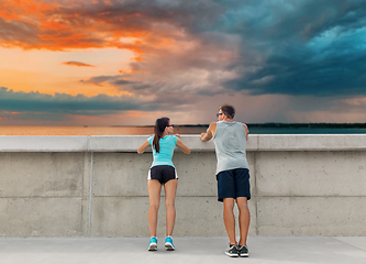 Image showing happy couple exercising outdoors at concrete wall