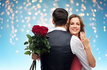 Image showing woman with engagement ring and roses hugging man