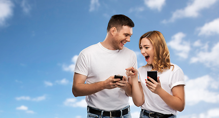 Image showing happy couple in white t-shirts with smartphones