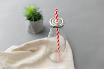 Image showing empty reusable glass bottle of with striped straw