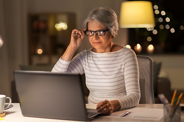 Image showing senior woman with laptop working at home at night