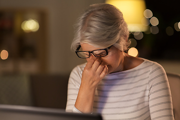 Image showing tired senior woman with laptop at home at night
