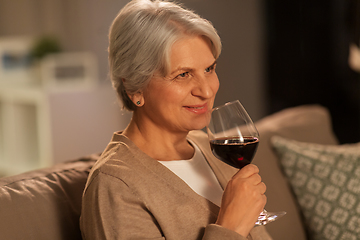 Image showing senior woman drinking red wine at home in evening