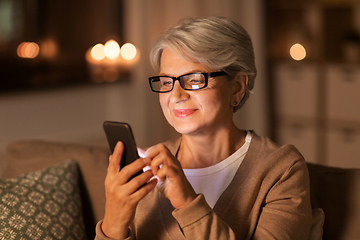 Image showing happy senior woman with smartphone at home