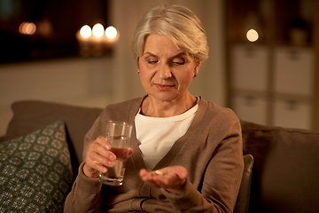 Image showing senior woman with water and medicine at home