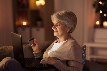 Image showing senior woman with laptop and credit card at night