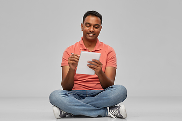 Image showing indian man in polo shirt writing to notebook