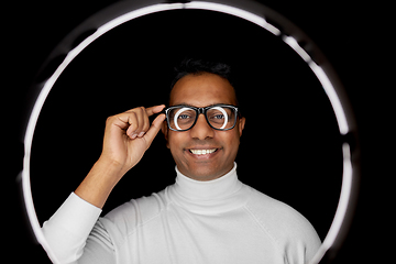 Image showing man in glasses over white illumination on black