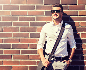 Image showing young man in sunglasses with bag over brickwall