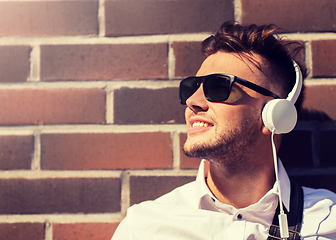 Image showing young man in headphones over brickwall