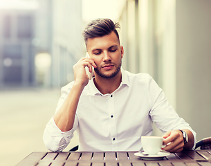 Image showing man with coffee calling on smartphone at city cafe