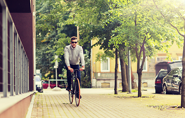 Image showing young man riding bicycle on city street