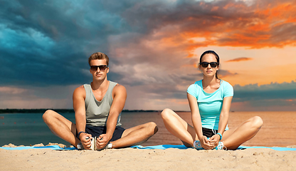 Image showing couple stretching legs on beach