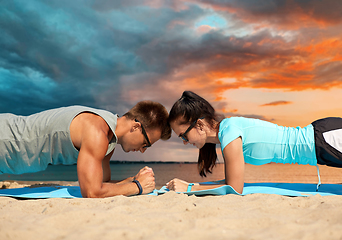 Image showing couple doing plank exercise on summer beach