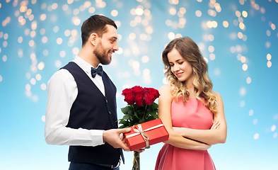 Image showing happy man giving woman flowers and present