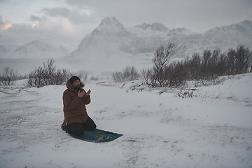 Image showing Muslim traveler praying in cold snowy winter day