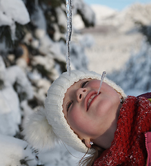 Image showing cute little girl while eating icicle on beautiful winter day