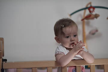 Image showing cute little one year old baby and making first steps in bed