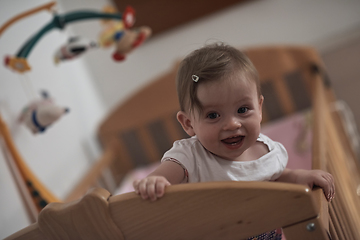 Image showing cute little one year old baby and making first steps in bed