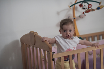 Image showing cute little one year old baby and making first steps in bed