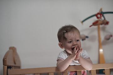 Image showing cute little one year old baby and making first steps in bed