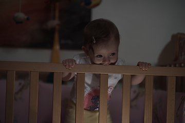 Image showing cute little one year old baby and making first steps in bed