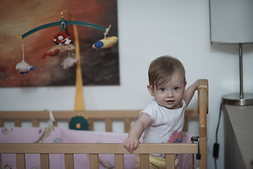 Image showing cute little one year old baby and making first steps in bed