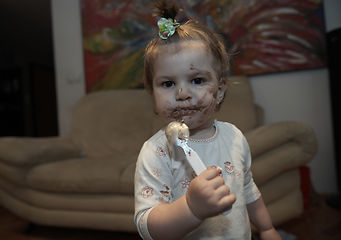 Image showing baby girl eating her chocolate desert with a spoon and making a mess