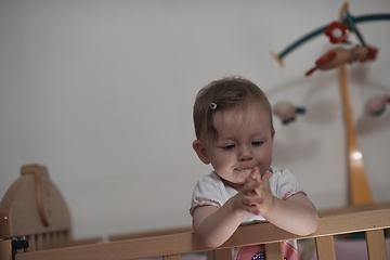 Image showing cute little one year old baby and making first steps in bed