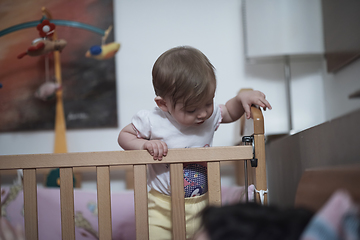 Image showing cute little one year old baby and making first steps in bed