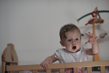 Image showing cute little one year old baby and making first steps in bed