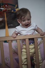 Image showing cute little one year old baby and making first steps in bed