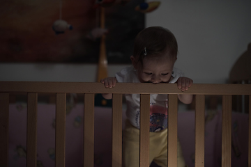 Image showing cute little one year old baby and making first steps in bed