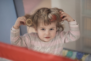 Image showing little baby girl with strange hairstyle and curlers