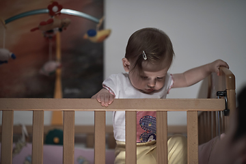 Image showing cute little one year old baby and making first steps in bed