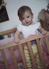 Image showing cute little one year old baby and making first steps in bed