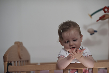 Image showing cute little one year old baby and making first steps in bed