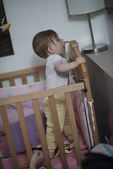 Image showing cute little one year old baby and making first steps in bed