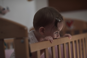 Image showing cute little one year old baby and making first steps in bed