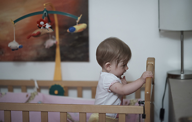 Image showing cute little one year old baby and making first steps in bed