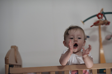 Image showing cute little one year old baby and making first steps in bed