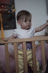 Image showing cute little one year old baby and making first steps in bed