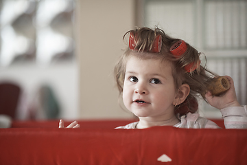 Image showing little baby girl with strange hairstyle and curlers
