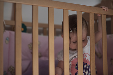 Image showing cute little one year old baby and making first steps in bed