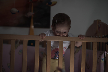 Image showing cute little one year old baby and making first steps in bed