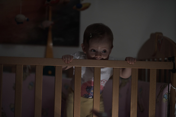 Image showing cute little one year old baby and making first steps in bed